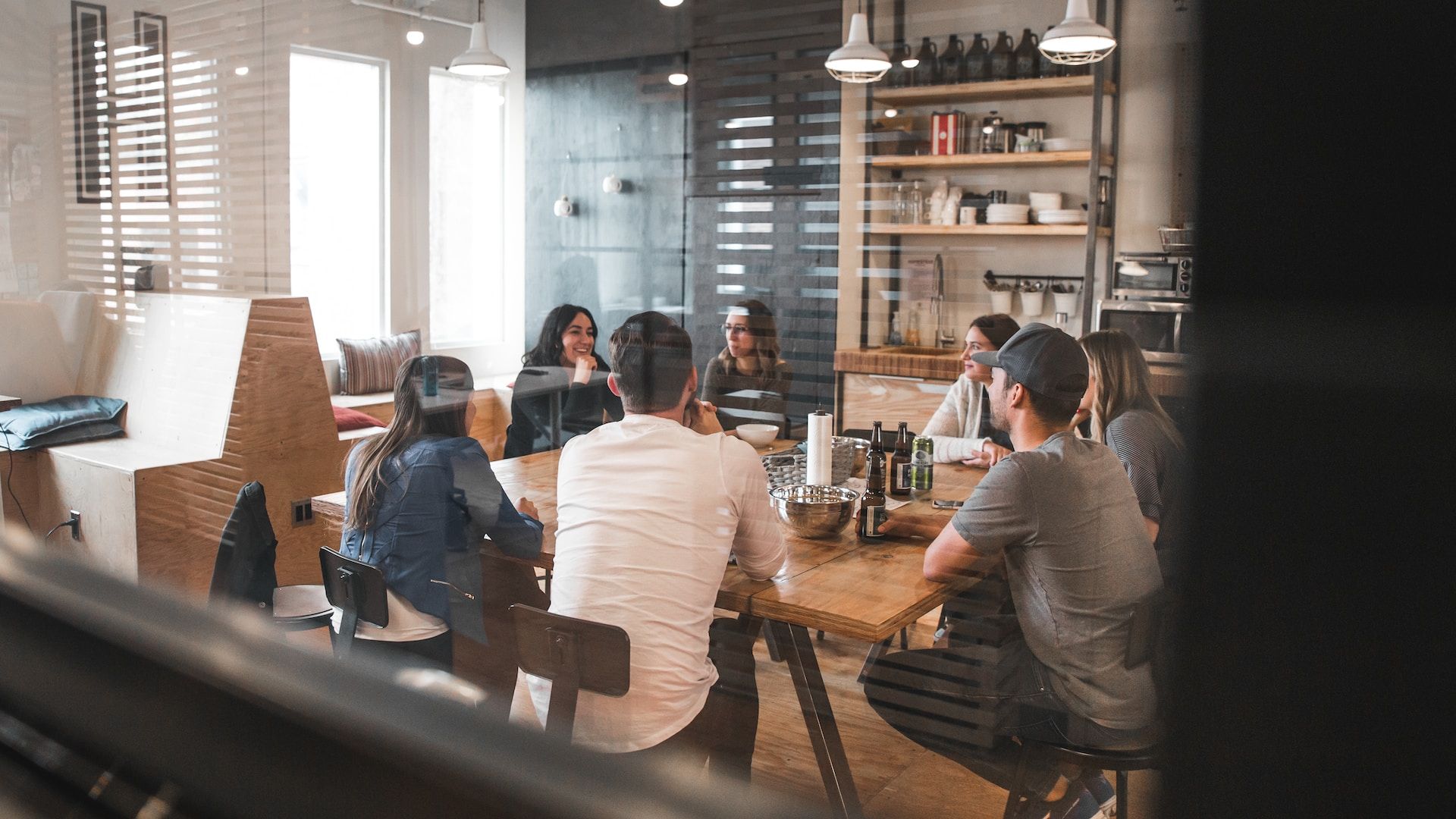 Several people sitting at a restaurant table, smiling and interacting while enjoying their dining experience together.